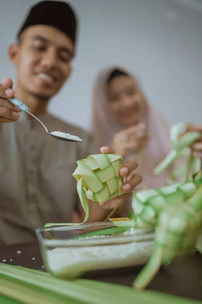 Muslim casal asiático fazendo ketupat arroz bolo em casa usando folha de palma — Fotografia de Stock
