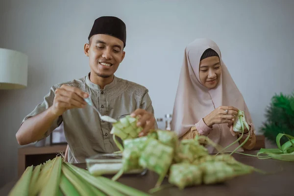Muslim casal asiático fazendo ketupat arroz bolo em casa usando folha de palma — Fotografia de Stock