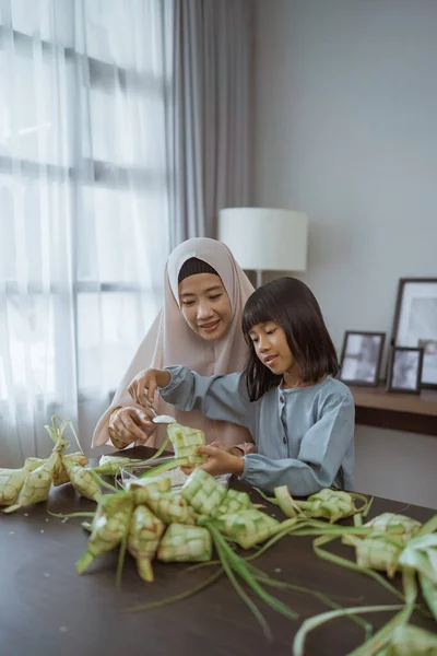 Moslim moeder en dochter maken ketupat voor eid mubarak — Stockfoto