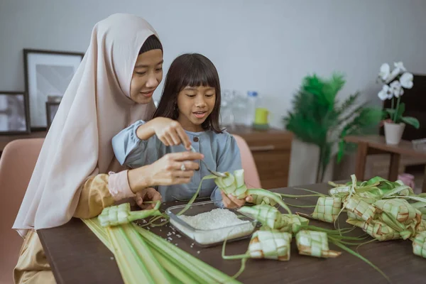 Mãe muçulmana ensinar sua filha como fazer um ketupat para eid mubarak — Fotografia de Stock