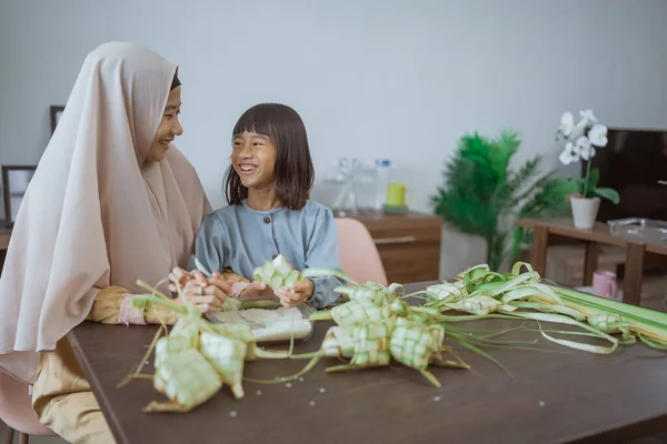 Mãe muçulmana ensinar sua filha como fazer um ketupat para eid mubarak — Fotografia de Stock