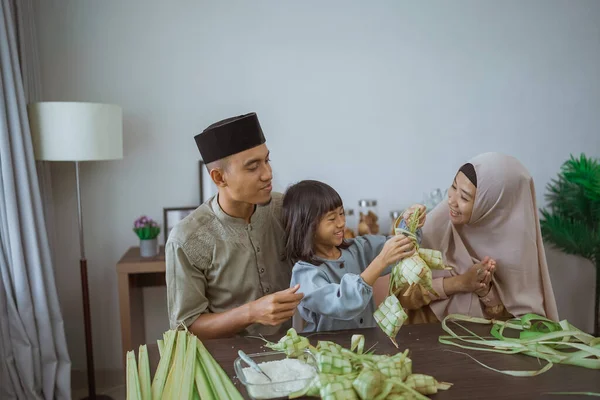 Kind met haar ouder het maken van een ketupat thuis — Stockfoto