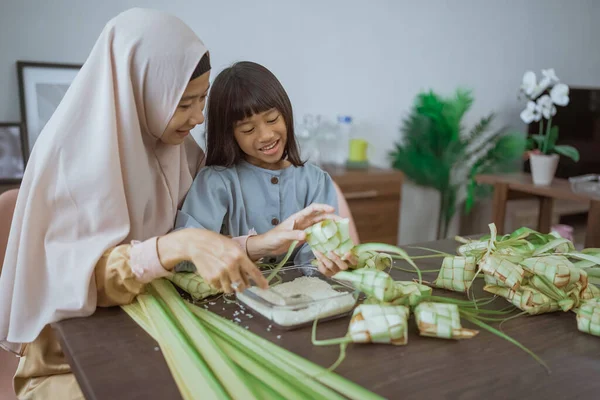 Muslim ibu dan anak membuat ketupat untuk eid mubarak — Stok Foto