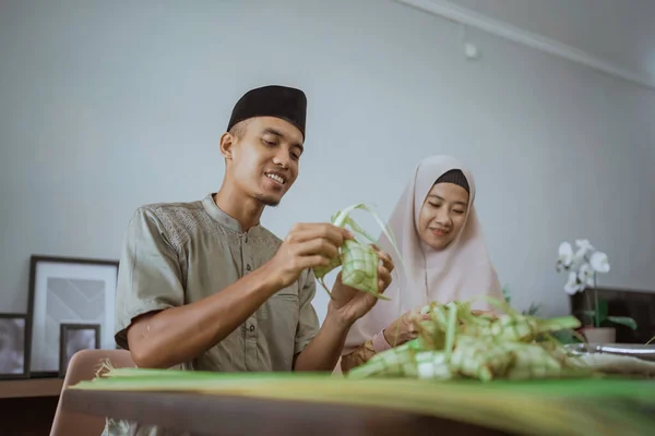Muslimska par asiatiska gör ketupat ristårta hemma med hjälp av palmblad — Stockfoto