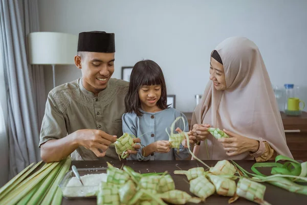 Kind met haar ouder het maken van een ketupat thuis — Stockfoto