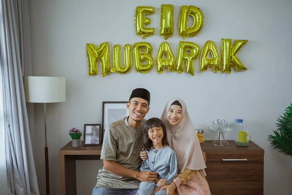 Keluarga muslim tersenyum sambil duduk di depan dekorasi barbar — Stok Foto