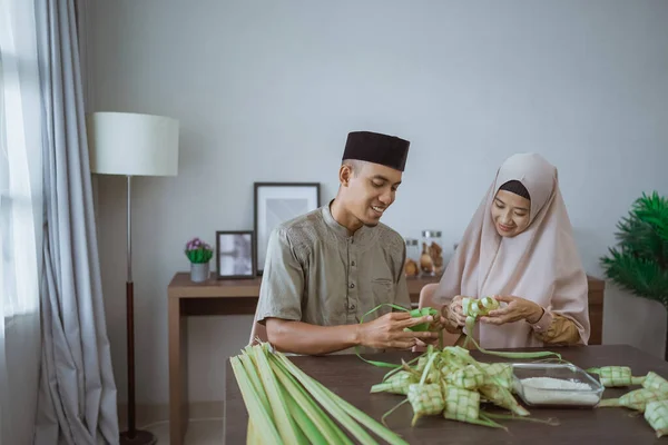 Musulmán pareja asiático haciendo ketupat arroz pastel en casa usando palma hoja — Foto de Stock