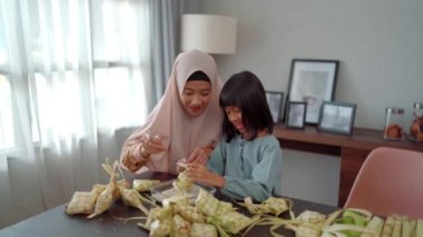 Müslüman anne ve kızı bayram mübareği için ketupat yapıyor.