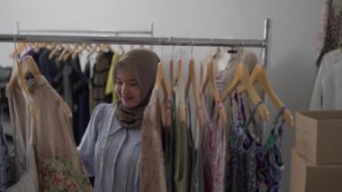 Müslüman moda tasarımcısı elbise ürünlerini kontrol ediyor.