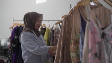 Müslüman moda tasarımcısı elbise ürünlerini kontrol ediyor.