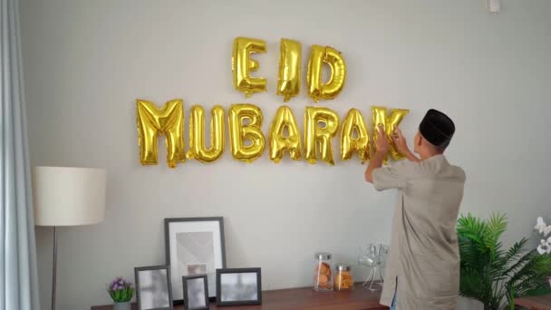 Pria muslim mendekorasi rumahnya dengan teks eid mubarak — Stok Video