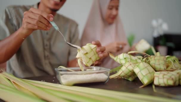 Мусульманская пара азиатской делать кетупат рисовый торт дома с помощью пальмового листа — стоковое видео