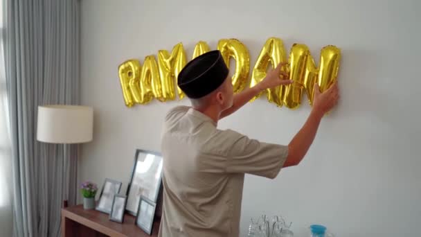 벽에 라마단 풍선 문자로 벽을 장식하고 있는 현수막 남자 — 비디오