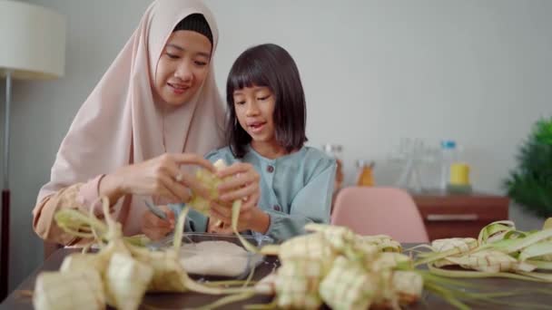 Muslim mother and daughter make ketupat for eid mubarak celebration with family — Stock Video