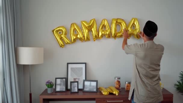 Moslim mannetje versiert de muur met ramadan ballon tekst op de muur — Stockvideo