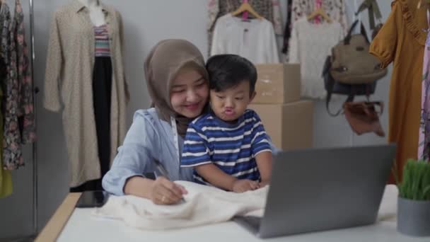 Muslimische Mutter mit Sohn arbeiten im Home Office — Stockvideo