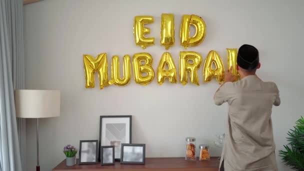 Muslim αρσενικό διακόσμηση του σπιτιού του με eid mubarak κείμενο — Αρχείο Βίντεο
