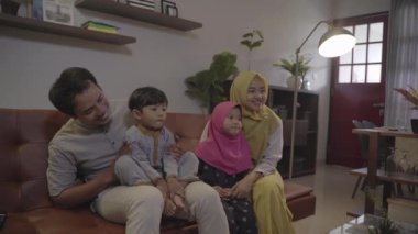Asyalı Müslüman aile oturma odasında eğleniyor.