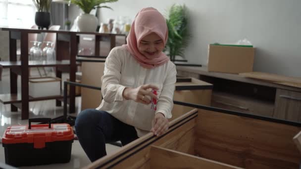 Muslim wanita perakitan perabotan baru di rumah — Stok Video
