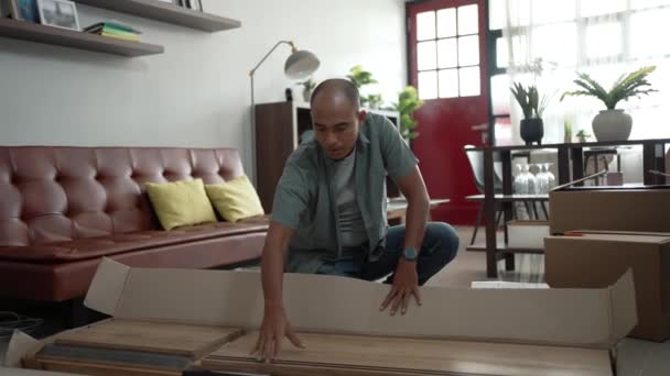 Hombre feliz mientras trabaja en el montaje de nuevos muebles — Vídeos de Stock