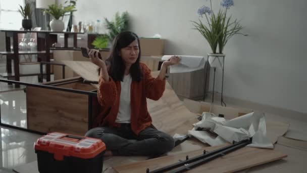 Разочарованная азиатская женщина во время сборки новой мебели — стоковое видео
