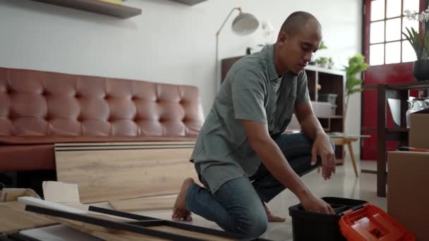 Молодой азиатский мужчина собирает мебель самостоятельно — стоковое видео