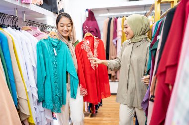 Elbise seçen kadın müşterilere servis yaparken peçeli garsonlar