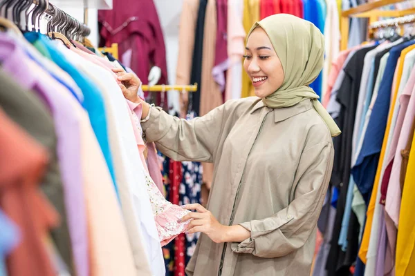 Hermosa mujer musulmana con pañuelo en la cabeza mirando un vestido — Foto de Stock