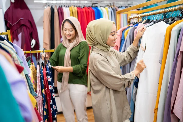 Мусульманська жінка купує нову сукню в магазині моди зі своїм другом — стокове фото
