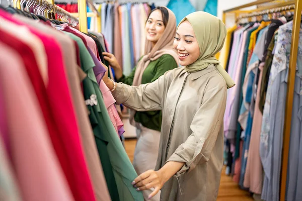 Krásná muslimka s hlavou šátek při pohledu na šaty — Stock fotografie