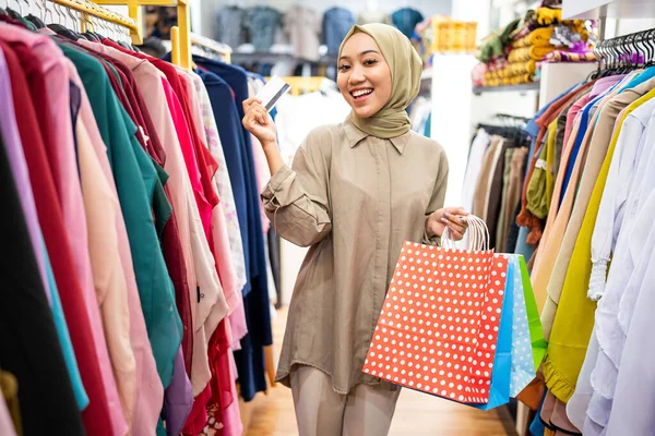 Mujer musulmana emocionada con bolsa de papel y tarjeta de crédito — Foto de Stock