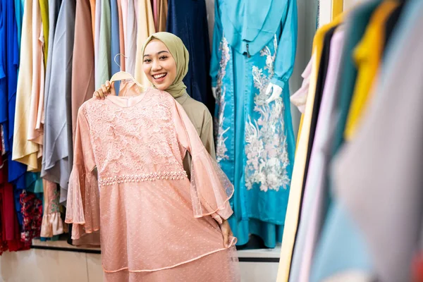 Güzel Müslüman kadın moda mağazasında yeni elbiseler deniyor.