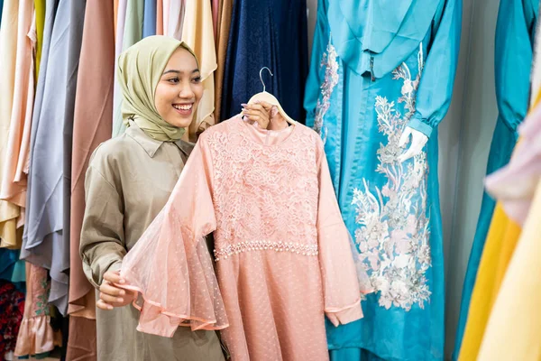 Heyecanlı Asyalı Müslüman kadın yeni kıyafetler deniyor. — Stok fotoğraf