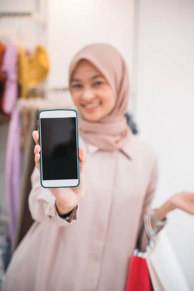 Beautiful girl wearing a hijab holding a smartphone and showing to camera — Stock Photo, Image