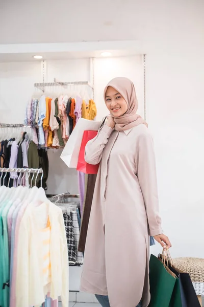 Zahalená dívka drží nákupní tašku v obchodě s oblečením s úsměvem na kameru — Stock fotografie