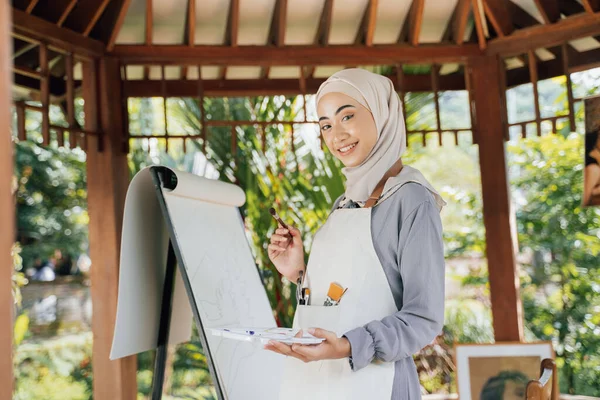 Muslim kvinnlig målare målning på duk i sin verkstad — Stockfoto