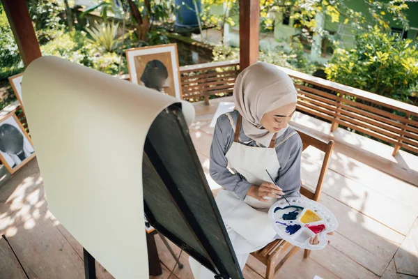 Художница-мусульманка рисует на холсте в домашней студии — стоковое фото