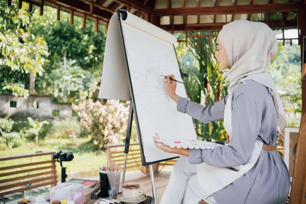 Muslim Žena umělkyně malba na plátně v domácím studiu — Stock fotografie