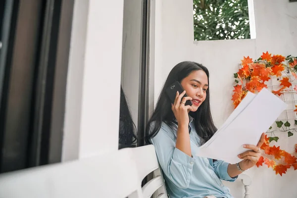 Vrouw praten over de telefoon tijdens het bespreken van haar papierwerk — Stockfoto