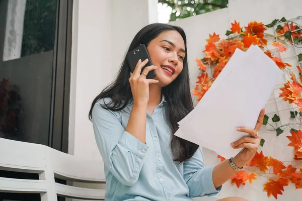 Vrouw praten over de telefoon tijdens het bespreken van haar papierwerk — Stockfoto