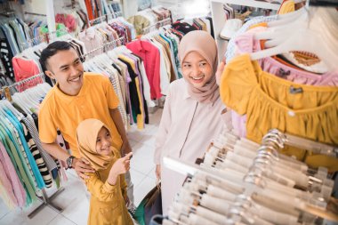 Asyalı Müslüman aile giyim mağazasından yeni kıyafetler alıyor.