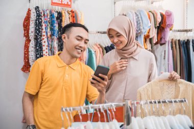 Dükkanda alışveriş yaparken akıllı telefonlara bakan çift.