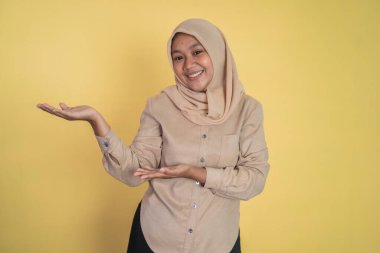 El hareketi yapan genç tesettürlü kadın bir şey sunuyor.