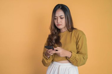 Üzgün Asyalı genç kadın izole edilmiş arka planda cep telefonu kullanırken