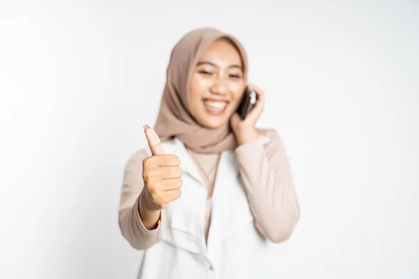 Mulher fazendo uma chamada usando um telefone celular e mostrando o polegar para cima — Fotografia de Stock