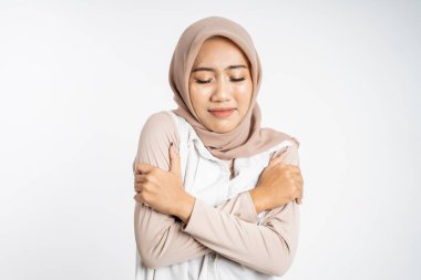 Müslüman kadın üşüyor, iki eli de vücuduna sarılıyor.