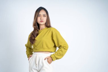 Güzel genç bir kadın iki eli pantolonun cebinde duruyor.