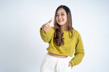 Çekici genç bir kadın, soyutlanmış arka planda başparmağıyla duruyor.