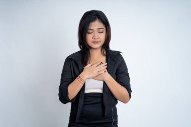 Asyalı genç bir kadın kendini rahatlamış hissederken göğsünü tutuyor