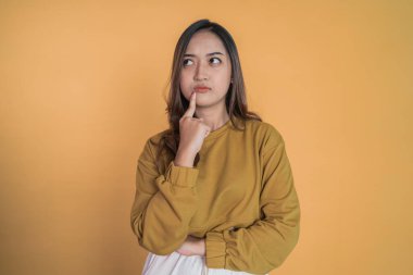 Genç Asyalı kadın parmak hareketleriyle bir şeyler düşünüyor.